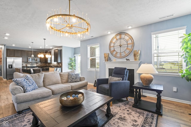 living room with wood-type flooring, a textured ceiling, and an inviting chandelier