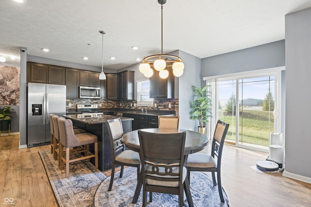 dining area featuring a wealth of natural light, a chandelier, and light wood-type flooring