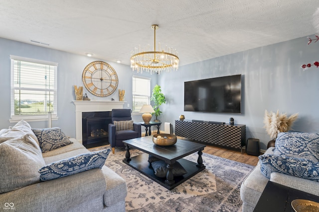 living room with hardwood / wood-style floors, a textured ceiling, and a notable chandelier