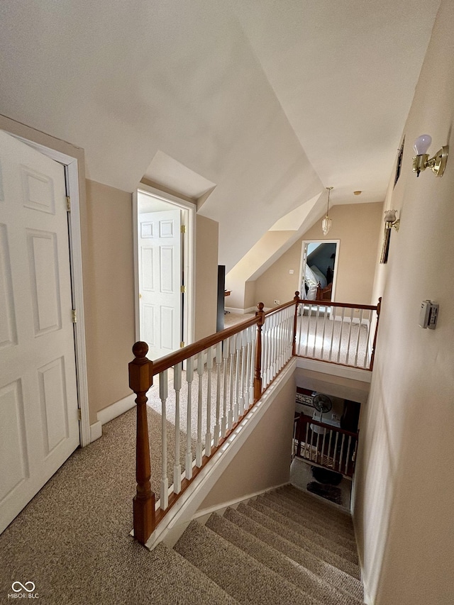 staircase featuring lofted ceiling, baseboards, and carpet flooring