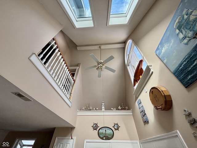 interior details with a ceiling fan, a skylight, and visible vents