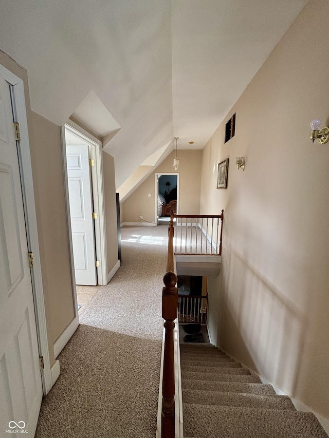 stairway with carpet floors, vaulted ceiling, and baseboards