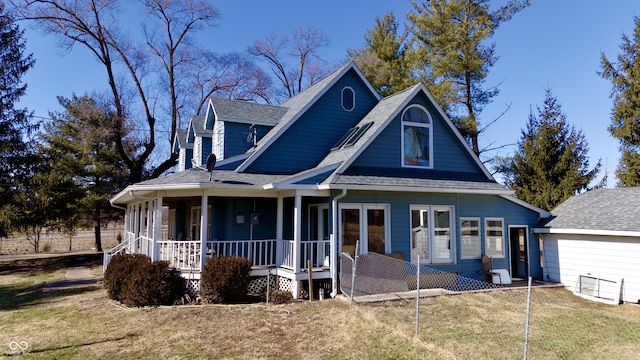 view of front of house with covered porch, roof with shingles, and a front yard