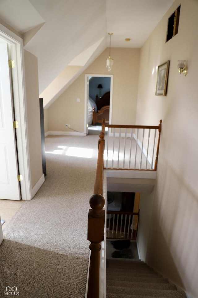 stairway featuring carpet, baseboards, and vaulted ceiling