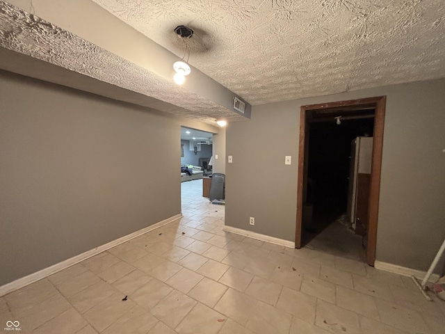 unfurnished room with a textured ceiling, visible vents, and baseboards