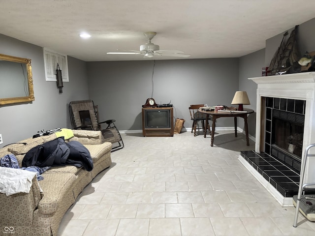 living room with a tile fireplace, ceiling fan, and baseboards