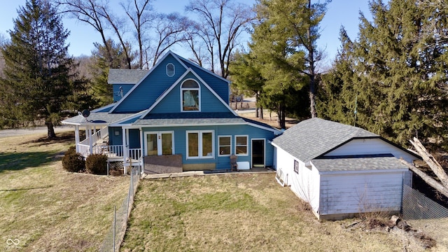 view of front of home with covered porch, a front lawn, an outdoor structure, and a shingled roof