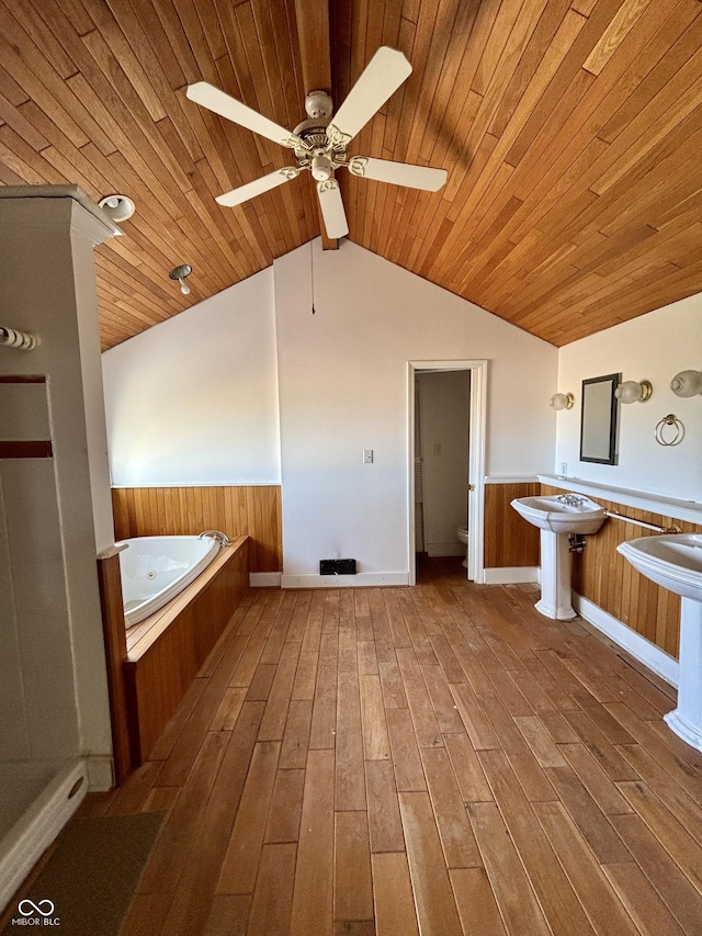 bathroom with a wainscoted wall, vaulted ceiling, toilet, and wood finished floors