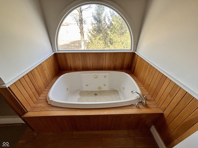 bathroom featuring a jetted tub and a wainscoted wall