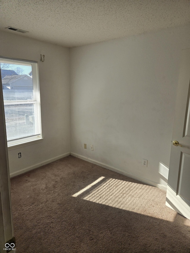 carpeted empty room featuring a textured ceiling