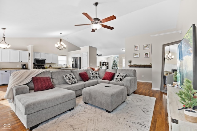 living room featuring lofted ceiling, light wood-type flooring, plenty of natural light, and ceiling fan with notable chandelier