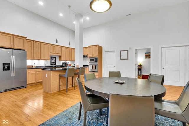 dining space featuring a high ceiling and light wood-type flooring