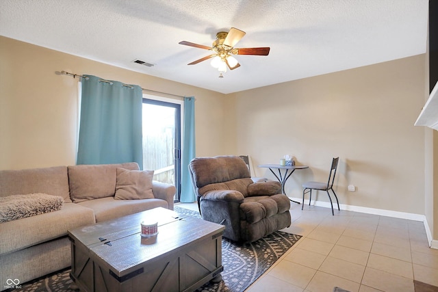 living room featuring ceiling fan, light tile patterned floors, and a textured ceiling