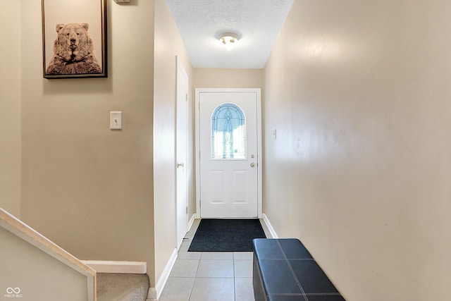 doorway to outside featuring light tile patterned flooring and a textured ceiling