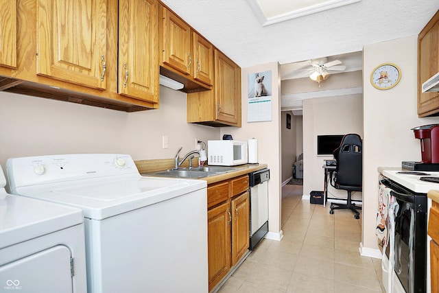 clothes washing area with a textured ceiling, ceiling fan, washing machine and dryer, and sink