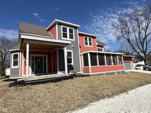 rear view of house with a garage and a sunroom