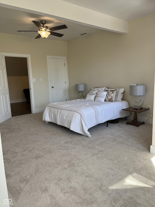 carpeted bedroom with ceiling fan and beamed ceiling