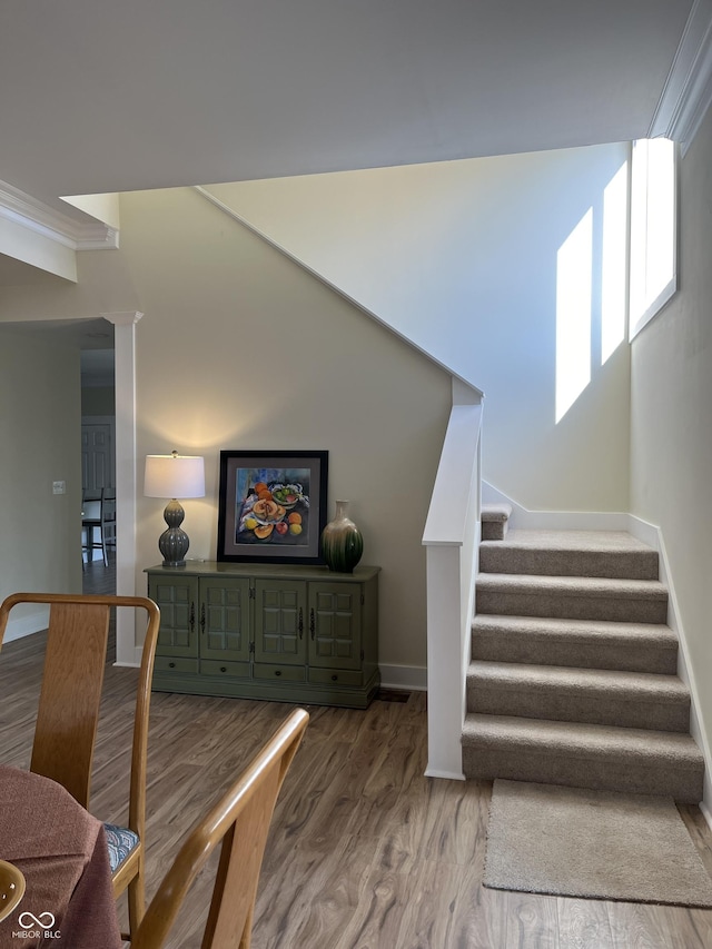 stairway featuring ornamental molding and wood-type flooring