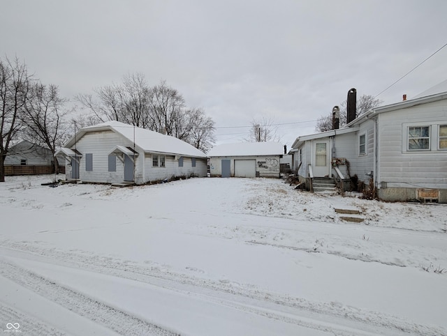 snow covered property with an outdoor structure and a garage