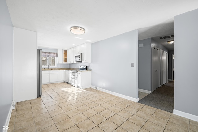 kitchen featuring sink, white cabinetry, stainless steel appliances, and light tile patterned floors