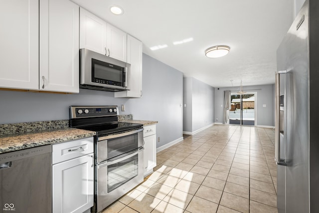 kitchen with light stone countertops, light tile patterned floors, stainless steel appliances, and white cabinetry