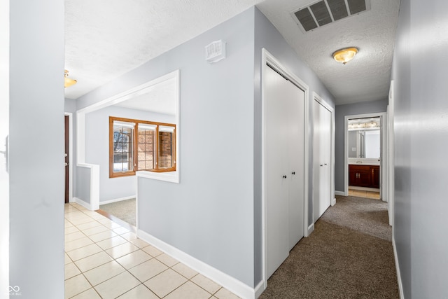 corridor featuring light carpet and a textured ceiling