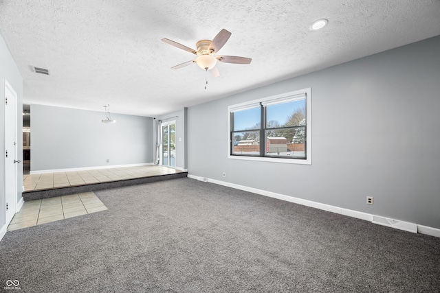 empty room with ceiling fan, light colored carpet, and a textured ceiling