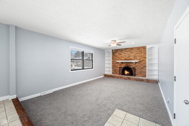 unfurnished living room with ceiling fan, built in features, light colored carpet, a textured ceiling, and a fireplace