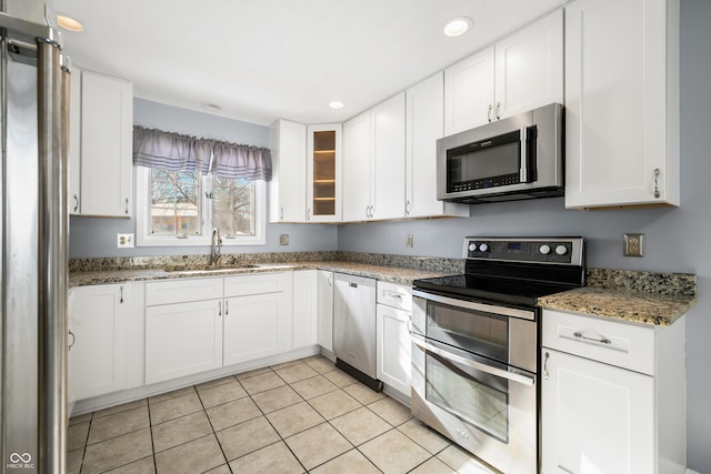 kitchen with light stone counters, white cabinetry, and stainless steel appliances