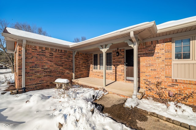 snow covered property entrance with covered porch