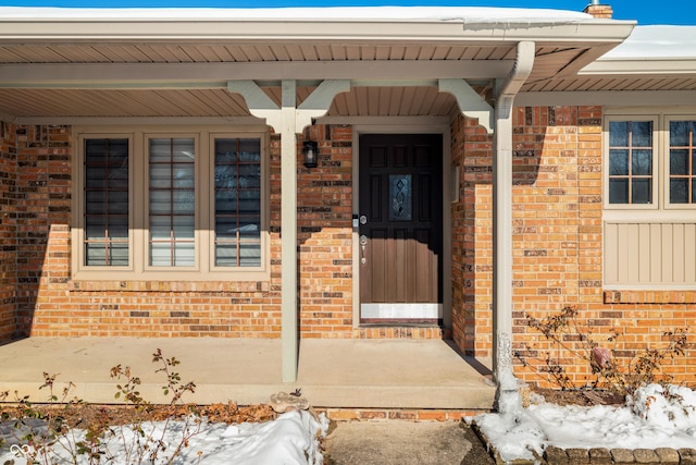 snow covered property entrance featuring covered porch