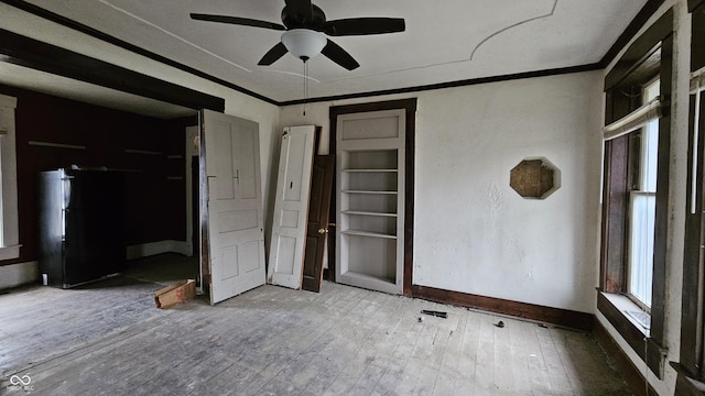 unfurnished bedroom featuring black fridge, ceiling fan, crown molding, and hardwood / wood-style floors