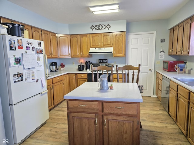 kitchen with a kitchen island, appliances with stainless steel finishes, sink, and light wood-type flooring