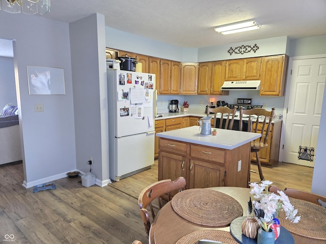 kitchen with white refrigerator, a kitchen island, and light wood-type flooring