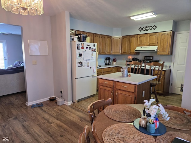 kitchen with a kitchen island, dark hardwood / wood-style floors, decorative light fixtures, white fridge, and an inviting chandelier