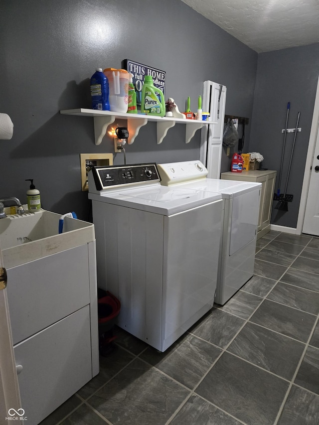 laundry area featuring independent washer and dryer, sink, and a textured ceiling