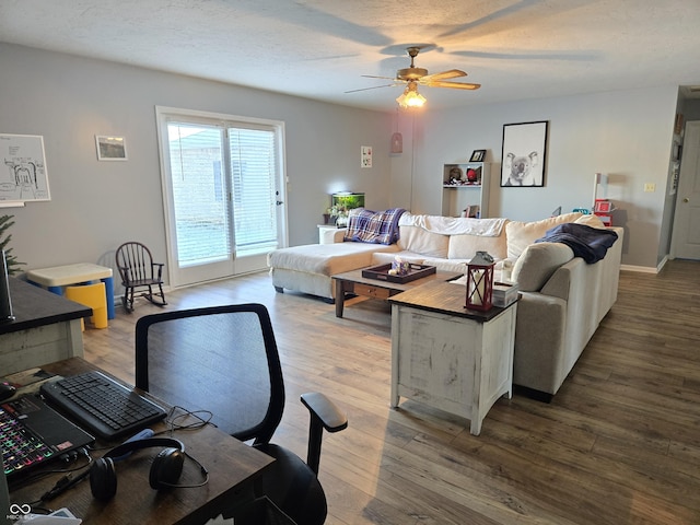 living room featuring hardwood / wood-style flooring, ceiling fan, and a textured ceiling