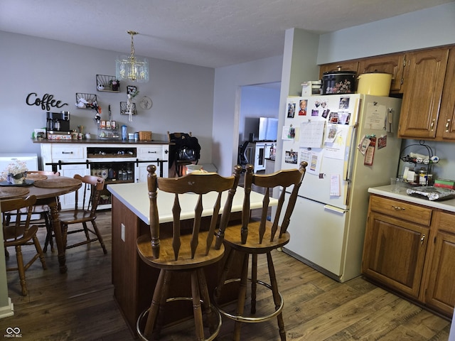 kitchen featuring pendant lighting, dark wood-type flooring, a chandelier, and white fridge