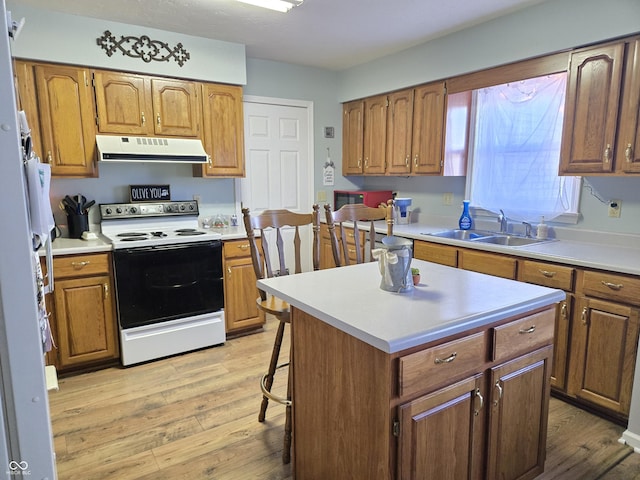 kitchen featuring white range with electric stovetop, sink, a kitchen breakfast bar, a center island, and light hardwood / wood-style flooring