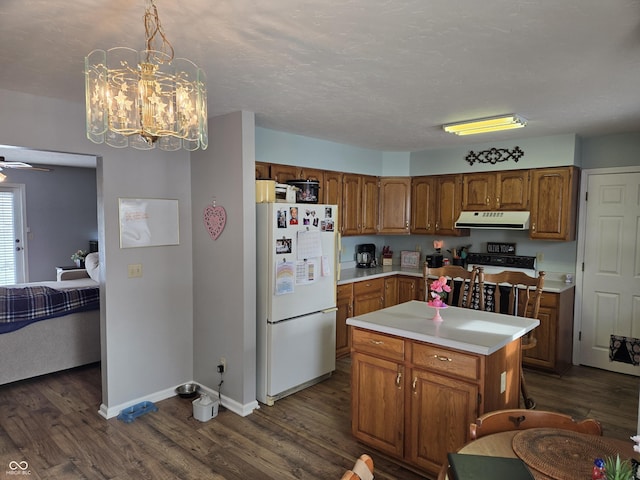 kitchen featuring ceiling fan, hanging light fixtures, white refrigerator, a kitchen island, and dark hardwood / wood-style flooring