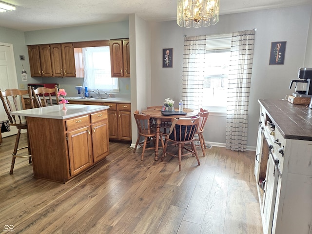 kitchen with wood-type flooring, a kitchen island, plenty of natural light, and decorative light fixtures