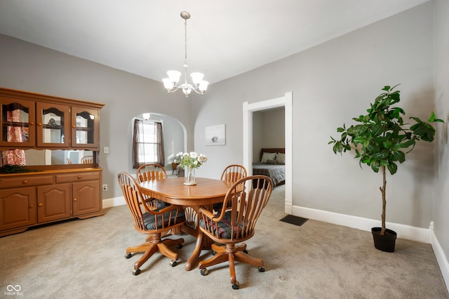 dining space featuring light carpet and a chandelier