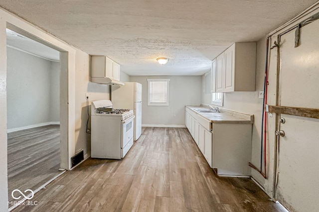 kitchen with light wood-type flooring, a textured ceiling, white appliances, sink, and white cabinets