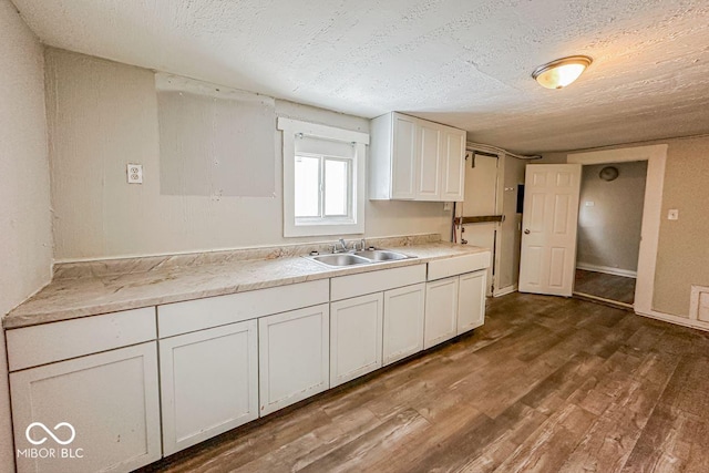 kitchen with a textured ceiling, white cabinets, sink, and dark wood-type flooring