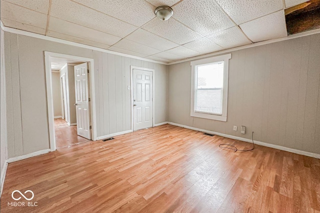 unfurnished bedroom featuring wooden walls, a drop ceiling, and wood-type flooring