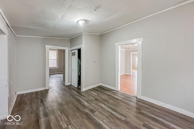 empty room featuring dark hardwood / wood-style flooring, ornamental molding, and a textured ceiling