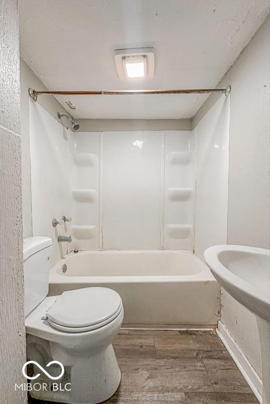 bathroom with hardwood / wood-style floors, shower / bath combination, and toilet