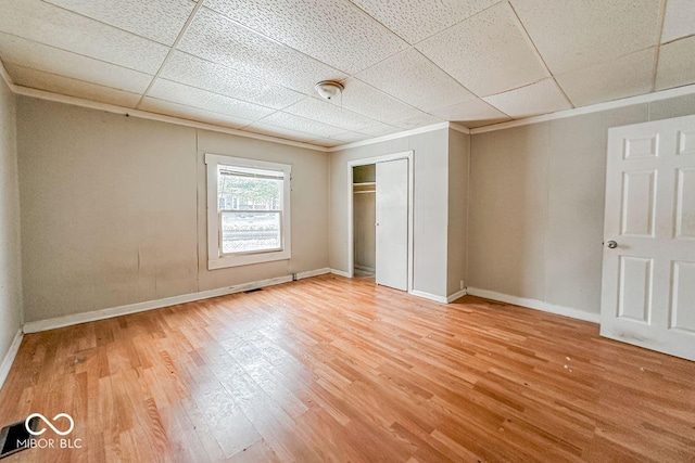 unfurnished bedroom with a drop ceiling, wood-type flooring, and a closet