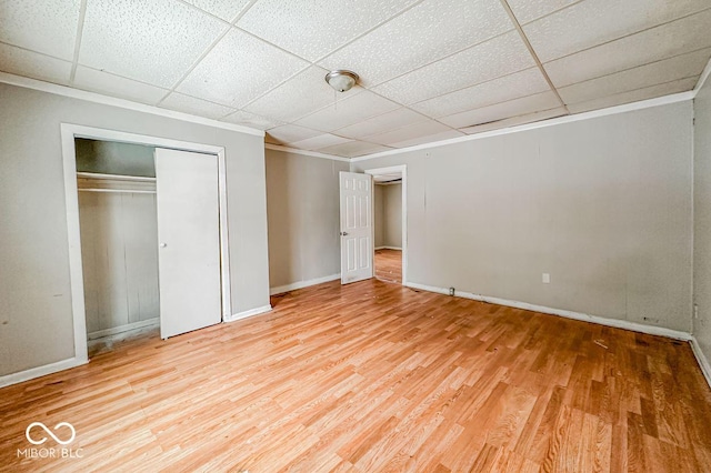 unfurnished bedroom with hardwood / wood-style flooring, a drop ceiling, and a closet