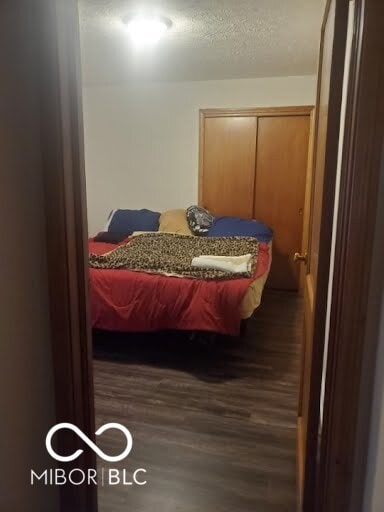 bedroom with dark hardwood / wood-style flooring and a closet